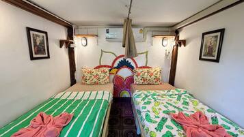 Habitación con dos camas, cada una con almohada y toalla. Cuenta con luces de pared y un ventilador de techo.