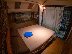 A room with a bed, a window with curtains, a wall with a painting, and a wooden floor. - Good Life Dacha (Pai)