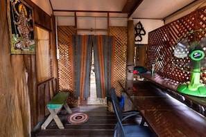 A room with a wooden bench, a patterned curtain, a green fan, and a wall with a lattice design. - Good Life Dacha (Pai)
