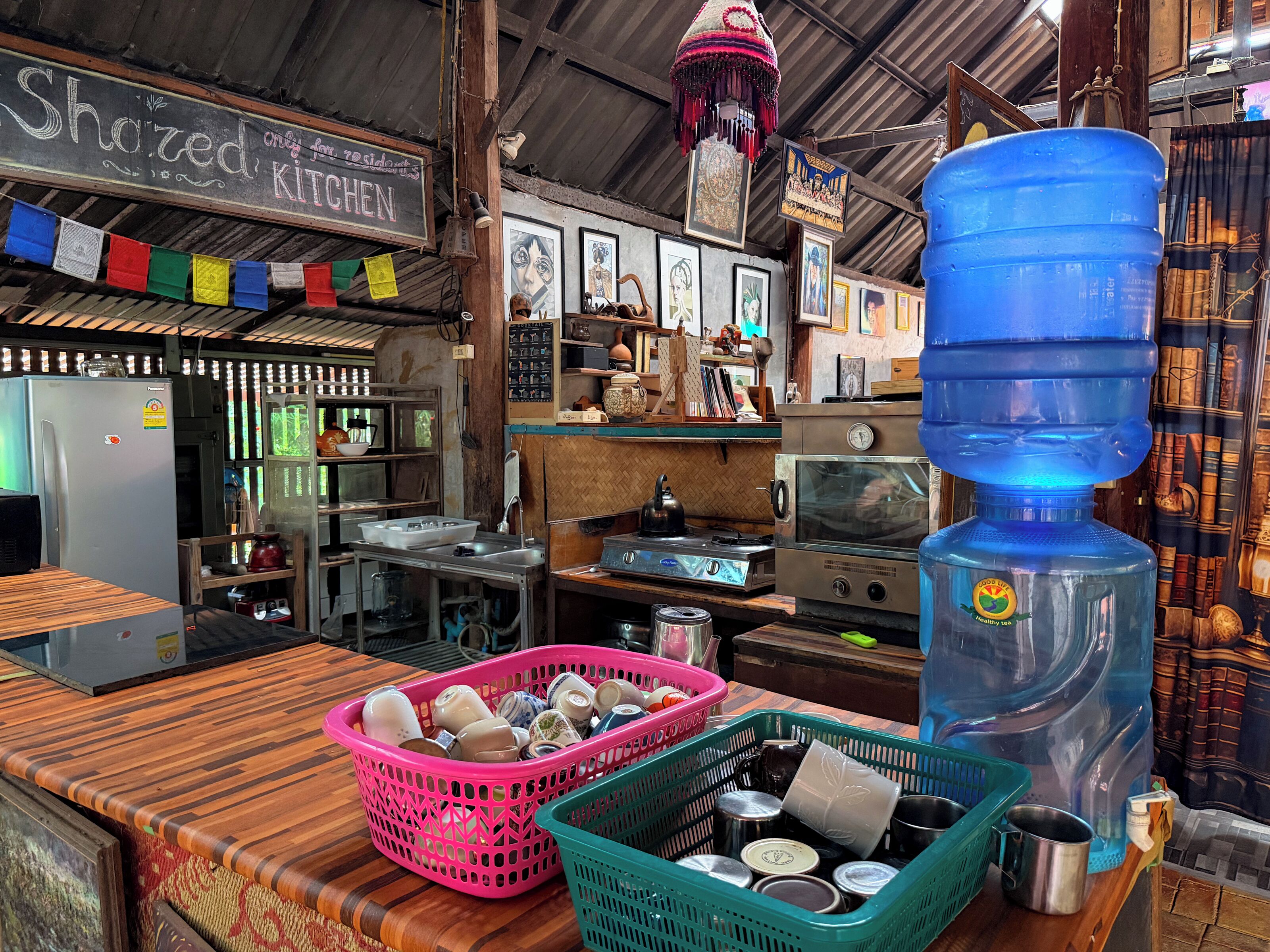 Una cocina equipada con refrigerador, pileta, cocina y un dispensador grande de agua.