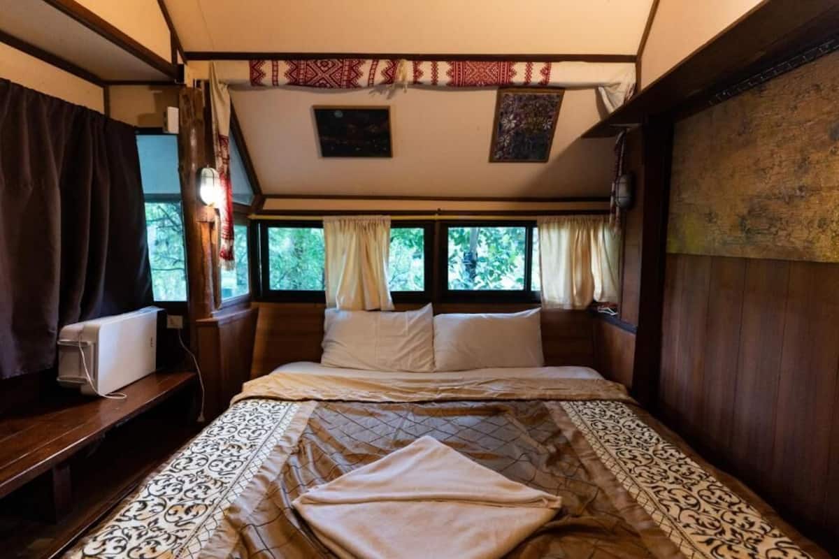A bedroom with a bed, a bedside table, a window, and a curtain.