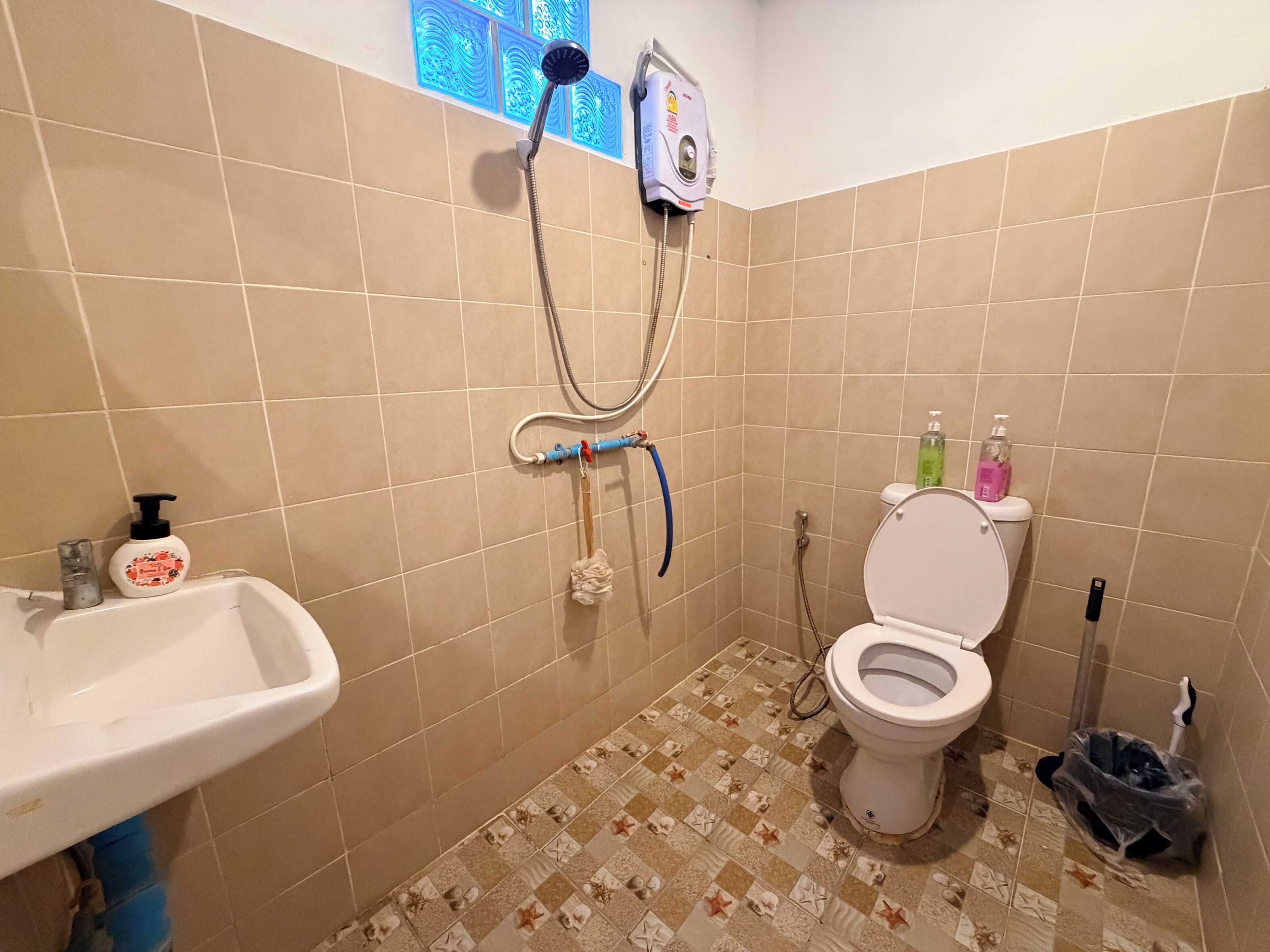 A bathroom with a toilet, sink, shower, and tiled floor.