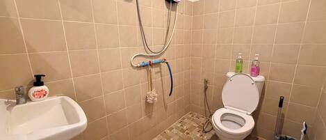 A bathroom with a toilet, sink, shower, and tiled floor.