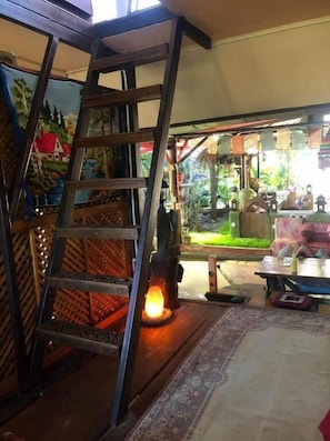 A wooden ladder, a lantern, and a small outdoor seating area with a table and chairs. - Good Life Dacha (Pai)