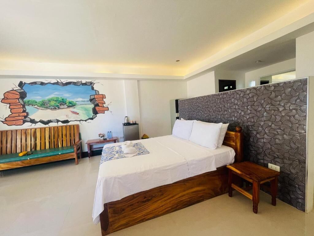 Una habitación de hotel con una cama, un banco de madera, un mural en la pared y un papel tapiz estampado.