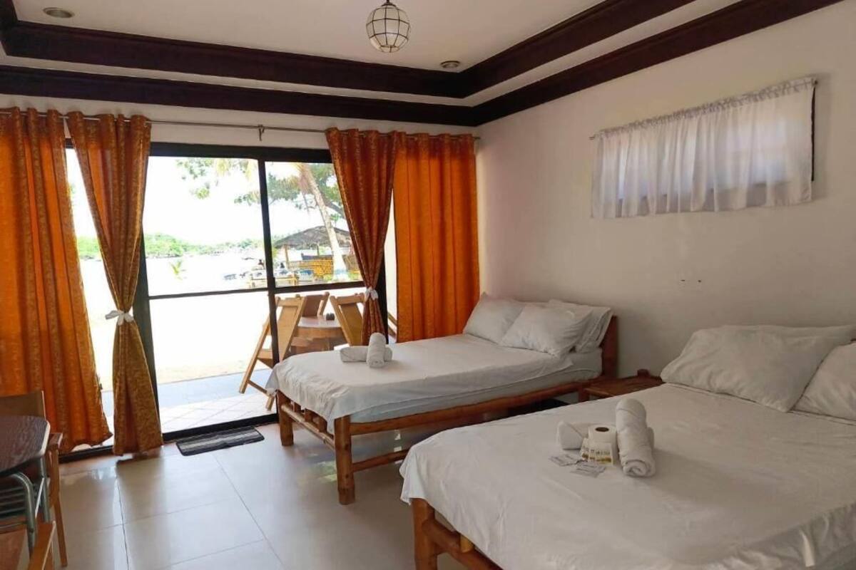 A room with two wooden beds, a chair, and a window with curtains.