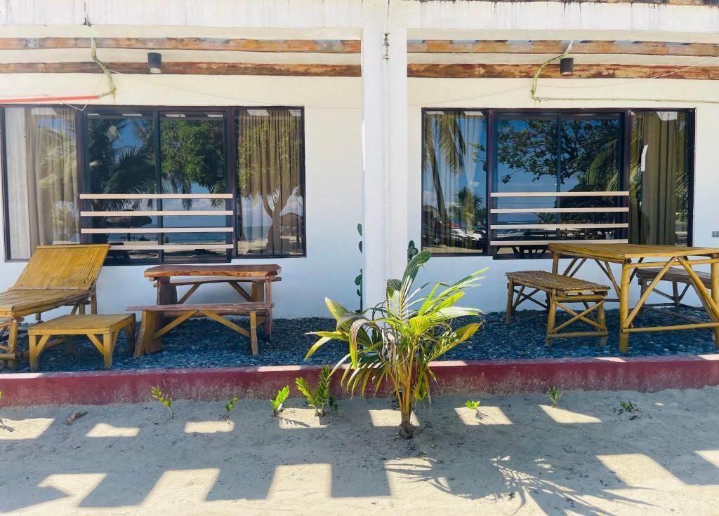 A beachfront property with a wooden deck, lounge chairs, and a small table.