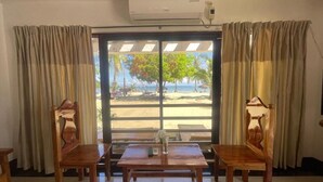 Una habitación con vista a la playa, una mesa con sillas y un equipo de aire acondicionado.