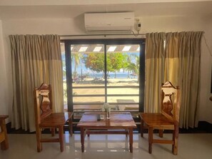 Une chambre avec vue sur la plage, une table avec des chaises et un appareil de climatisation.