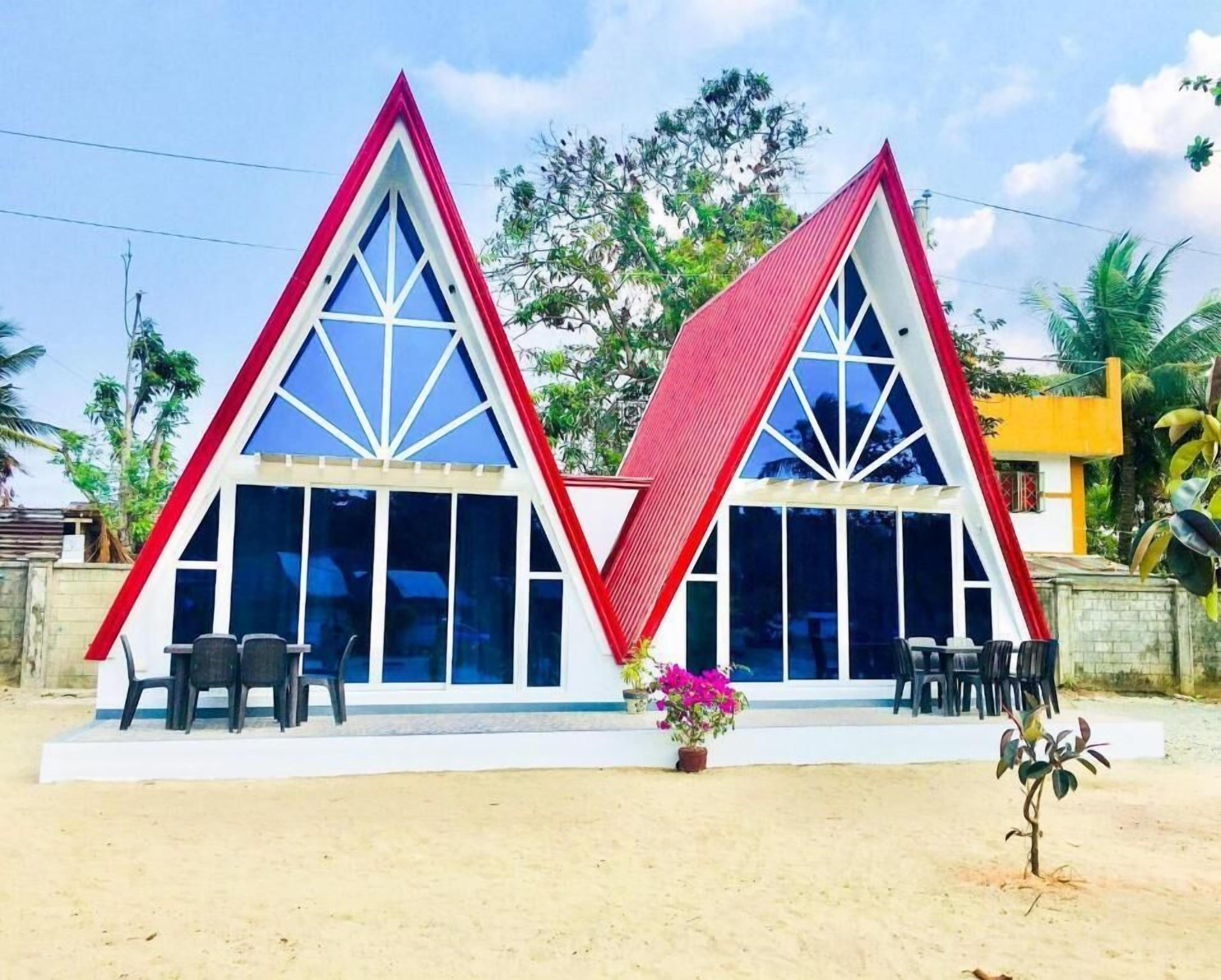 Un bâtiment à deux étages aux couleurs rouge et blanche, doté de grandes fenêtres et d’un espace extérieur aménagé pour s’asseoir.