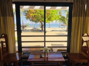 A beach view from a room with a table, chairs, and a vase of flowers. - Bolo Hills Beach Club (Alaminos)