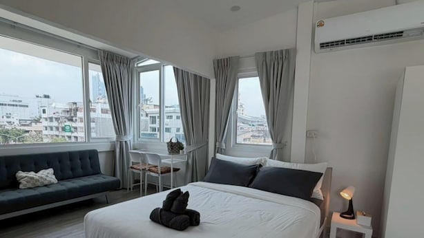 A hotel room with a bed, a sofa, a small table, and a lamp. - Prime Silom (Bangkok)