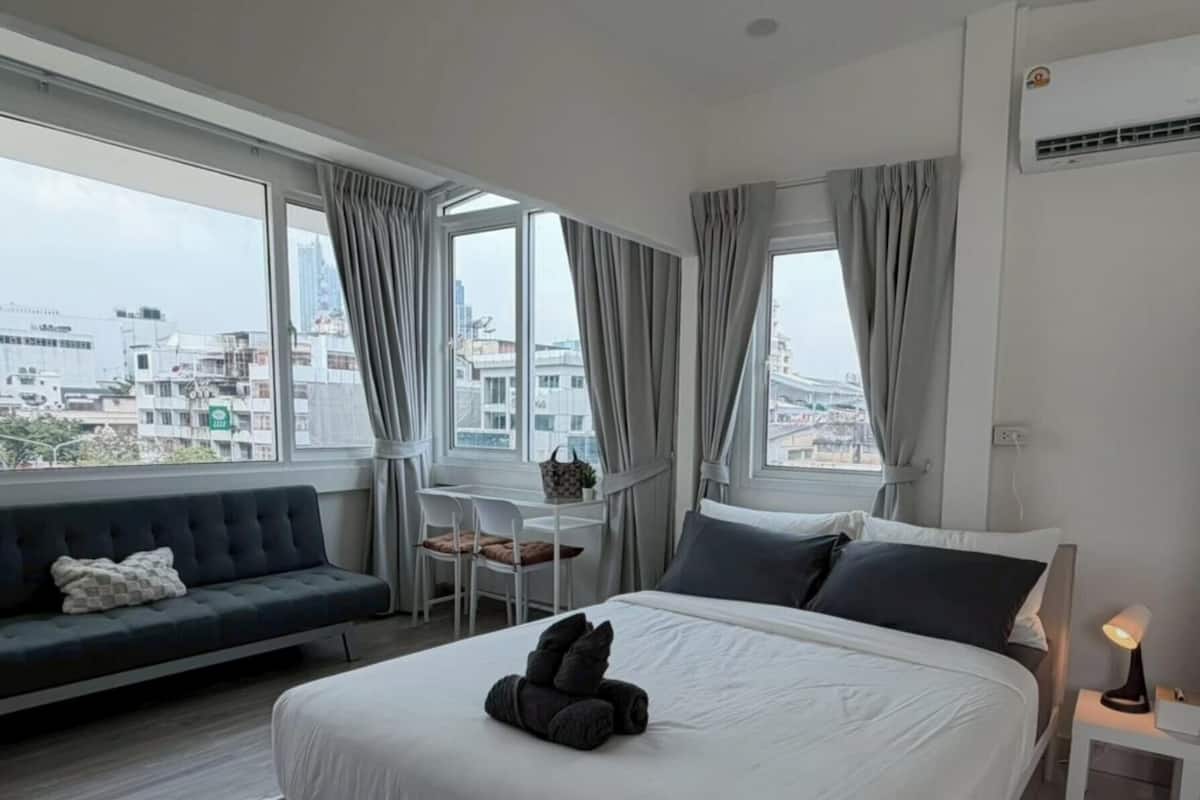 Una habitación de hotel con cama, sofá, una mesita y una lámpara.