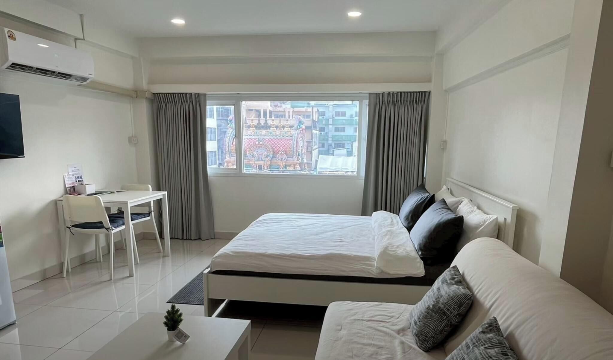 A hotel room with a bed, a desk, a chair, a TV, and a window with curtains.