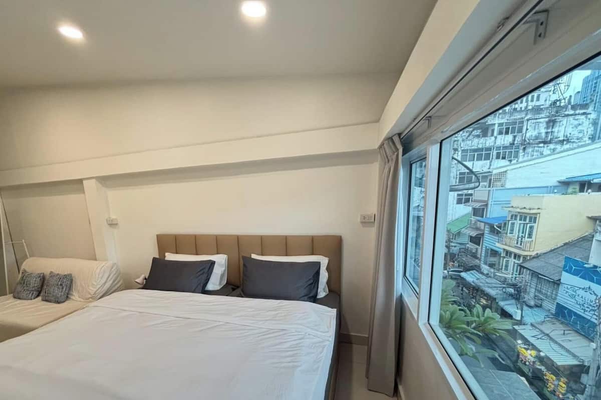 Un dormitorio con dos camas, un armario y un amplio ventanal con vistas a la ciudad.