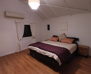 A bedroom with a bed, a nightstand, a window with curtains, and a ceiling light.