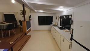 Una cocina moderna con gabinetes blancos, encimera negra y un televisor Hisense montado en la pared.