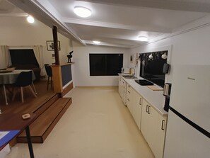 A modern kitchen with white cabinets, a black countertop, and a Hisense TV mounted on the wall. - Beautiful Byron hinterland retreat. 20 mins to Byron Bay, Bangalow and Ballina. (Clunes)