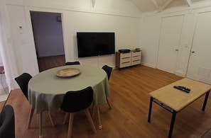 Ein Essbereich mit einem runden Tisch, Stühlen, einem Fernseher und einem kleinen Tisch mit einer Fernbedienung.