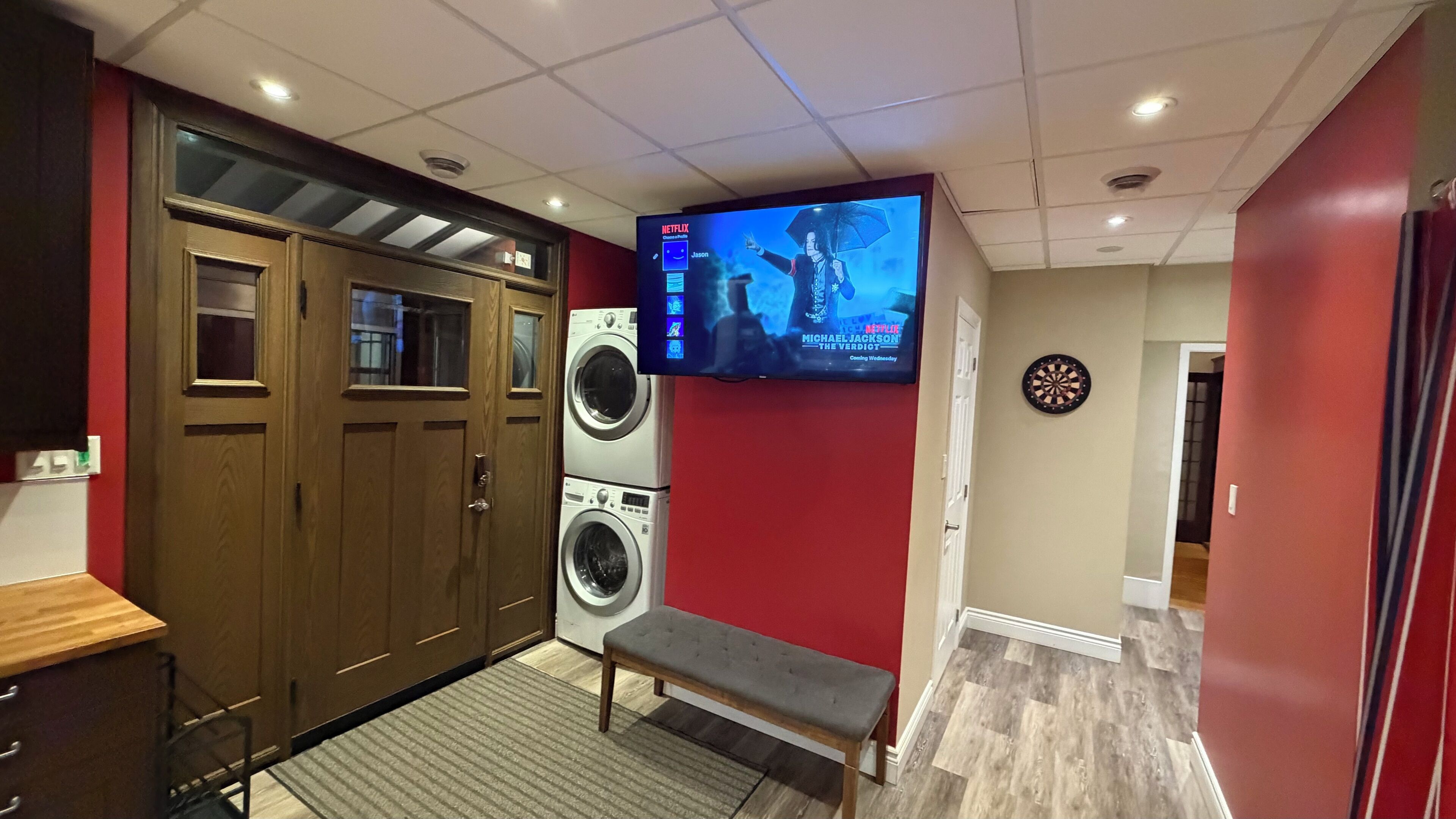 Una sala de lavandería con televisor, banco y dardo.