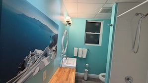 Un bagno con una parete blu, un mobile lavabo in legno, un lavandino bianco, un water e una doccia.