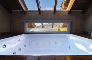 Un bain à remous avec vue sur les montagnes, grâce à une ouverture dans le toit.
