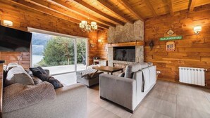 A cozy log cabin interior with a stone fireplace, wooden walls, and a sofa set.