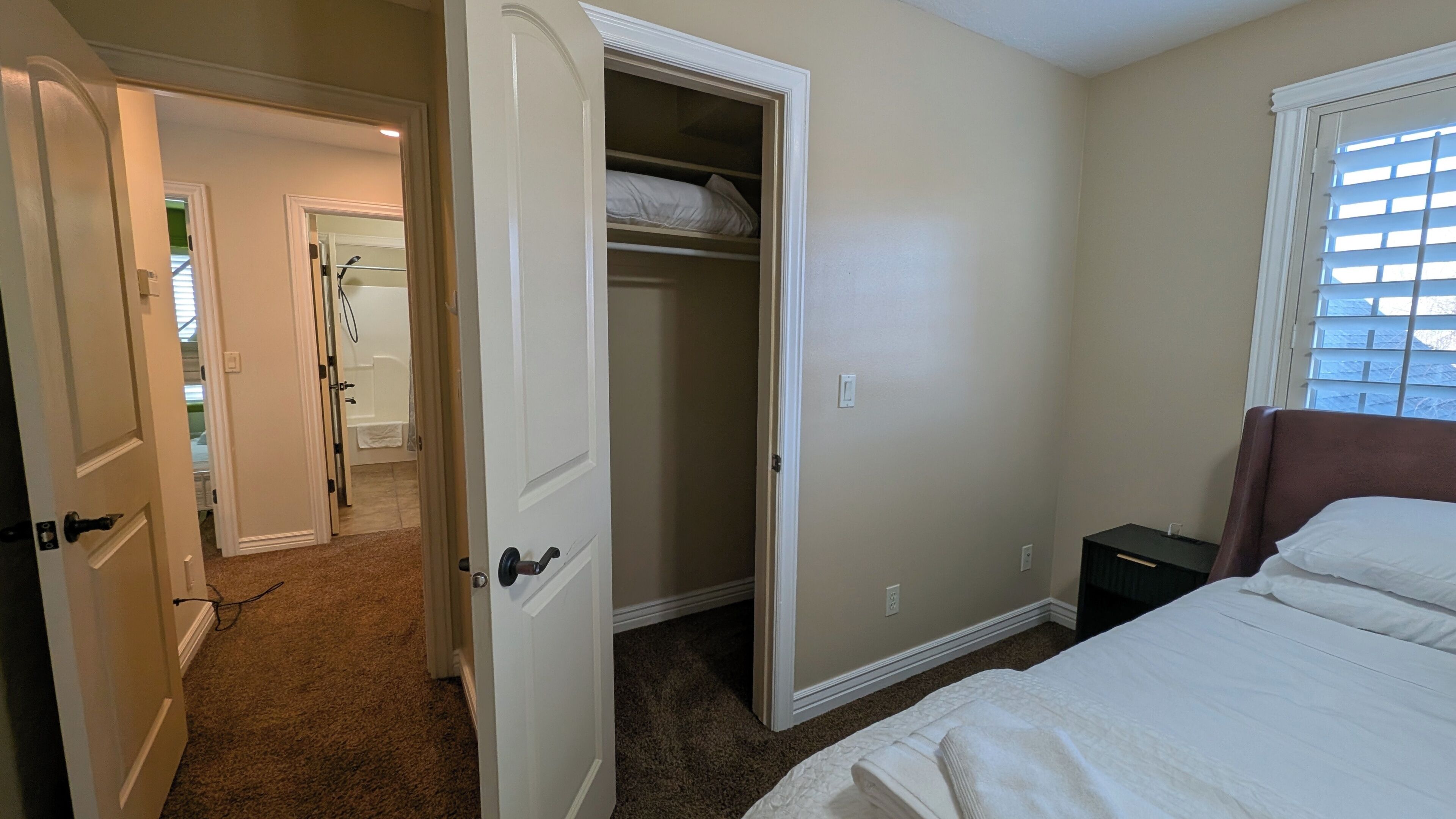 A bedroom with a bed, a closet, and a window.