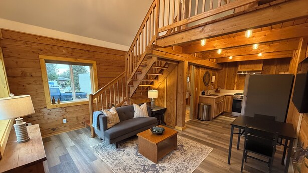 A wooden interior with a sofa, coffee table, and a staircase.