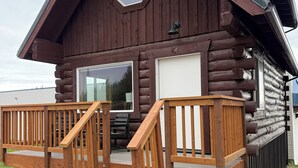 A log cabin with a wooden deck, a large window, and a garage.