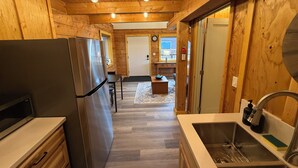 A wooden interior with a kitchen area, including a refrigerator, sink, and wooden cabinets.