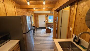 Un intérieur en bois comprenant un espace cuisine, avec un réfrigérateur, un évier et des placards en bois.
