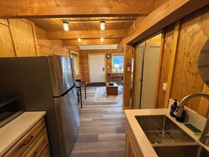 A wooden interior with a kitchen area, including a refrigerator, sink, and wooden cabinets.