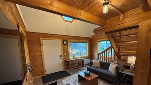 A wooden interior with a sofa, table, and staircase.