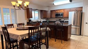 A kitchen with wooden cabinets, a dining table with chairs, a refrigerator, and a microwave. - El Paso | Large Group + RV Parking (El Paso)