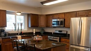 A kitchen with wooden cabinets, a stainless steel refrigerator, a microwave, and a gas stove. - El Paso | Large Group + RV Parking (El Paso)