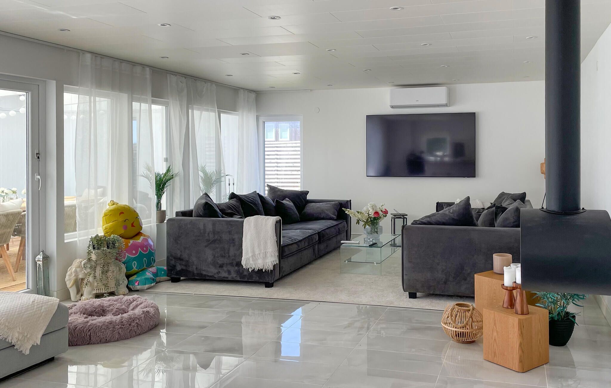 A modern living room with a grey sofa, a glass coffee table, and a large TV.