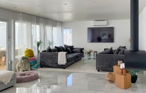 Ein modernes Wohnzimmer mit einem grauen Sofa, einem Glastisch und einem großen Fernseher.