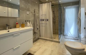 Une salle de bain moderne équipée d’une douche, de toilettes et d’un meuble-lavabo.
