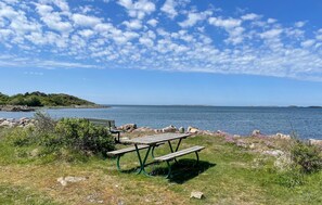 Une table de pique-nique au bord d’un lac, sous un ciel dégagé.