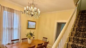 Una sala da pranzo con tavolo in legno, sedie, un lampadario e una scala con tappeto decorato.