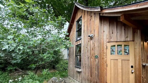 Una baita di legno con un vialetto in pietra che conduce alla porta, immersa nel verde.