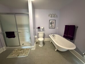 Un baño con ducha a nivel del suelo, inodoro y bañera independiente.