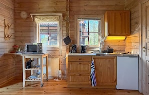 Eine kleine Küchenzeile in einem Holzchalet mit Mikrowelle, Kaffeemaschine und Spüle.