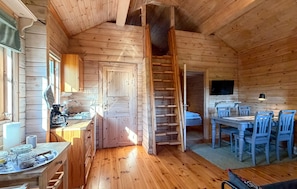 Ein Holzblockhaus-Interieur mit Küche, Essbereich und einer Treppe.