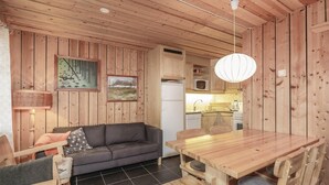 Een houten interieur met een bank, eettafel en keukenhoek.