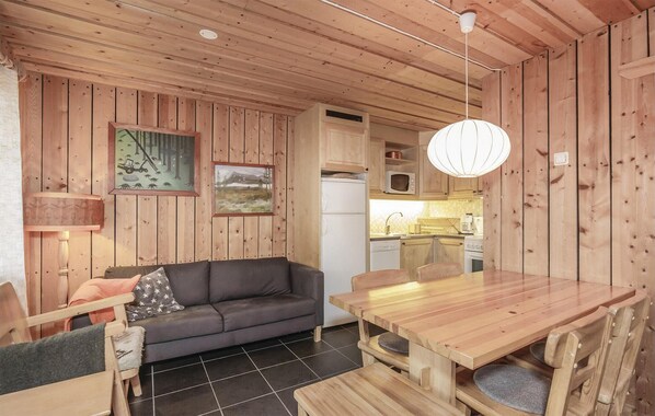 A wooden interior with a sofa, dining table, and kitchen area.