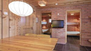 Een houten interieur met een eettafel, stapelbedden en een televisie.