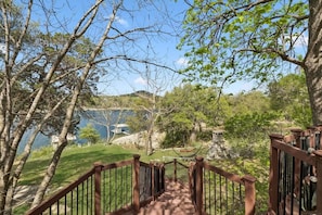 A wooden staircase leading to a scenic overlook with a view of a lake and distant buildings. - Charming Waterfront Cabin on Lake Travis (Leander)