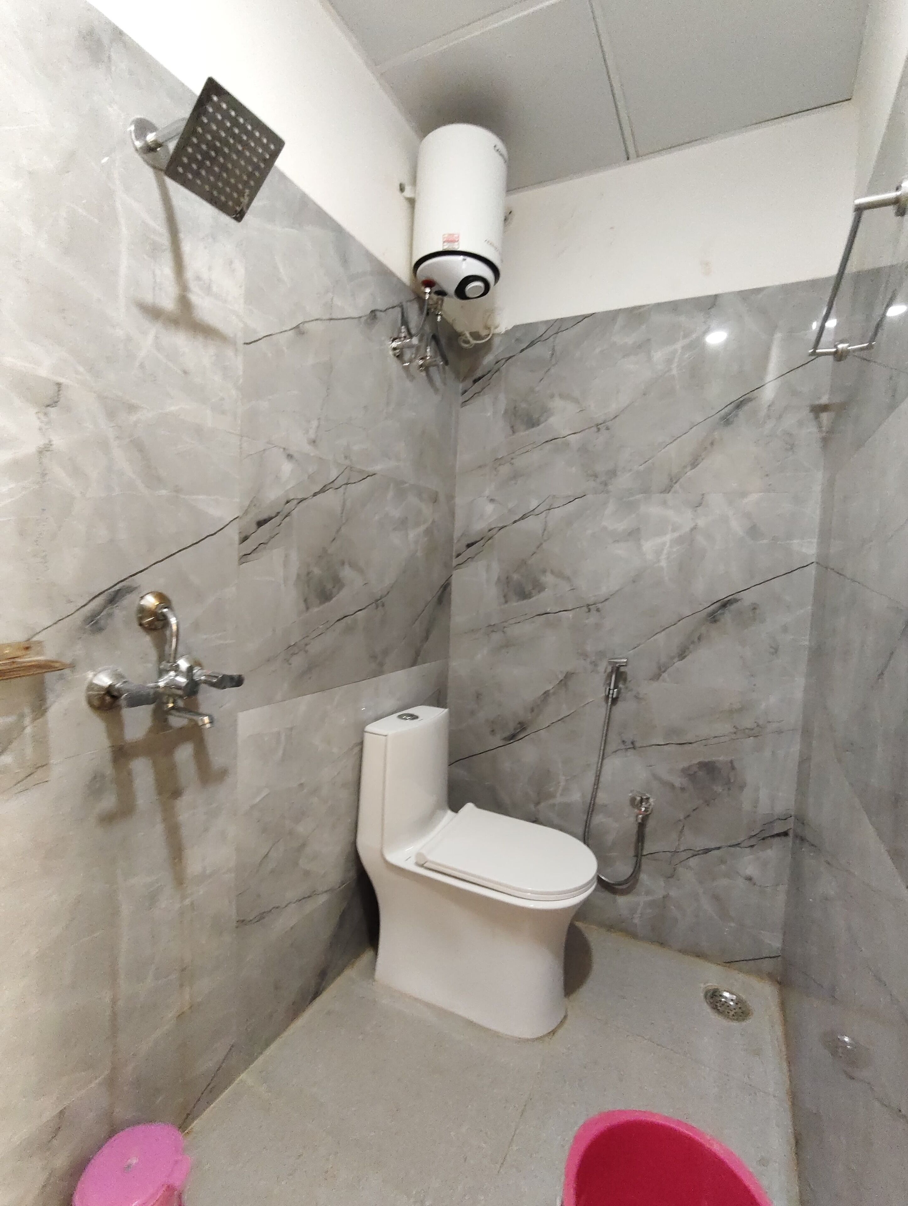 Een badkamer met toilet, douche en een toiletrolhouder.